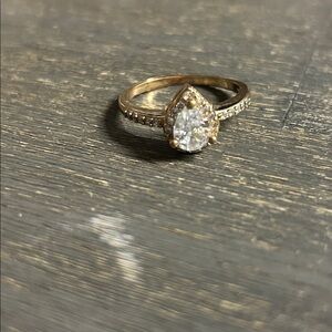 pear-shaped halo ring featuring a moissanite center stone and a pavé band‎